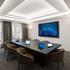 A conference room with a large display and in-ceiling speakers.