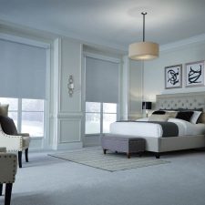 Bedroom with Lutron’s motorized window shades half lowered.