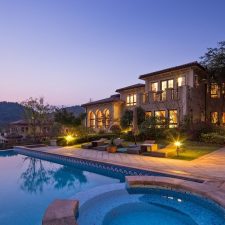 Modern home exterior illuminated by layered landscape lighting at night