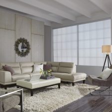 Beautiful, bright, modern living room with motorized window treatments and a large window.