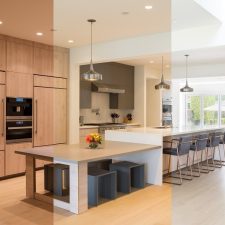 Open-plan kitchen shown with warm lighting on the left and cool daylight-balanced lighting on the right.