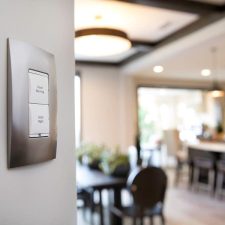 Control4 lighting keypad beside an open-plan kitchen and dining area