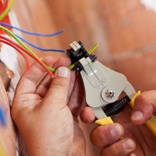 Technician stripping a low-voltage cable during a residential pre-wire installation.