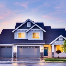 Two-story home illuminated at dusk with a three-car garage and landscaped front yard