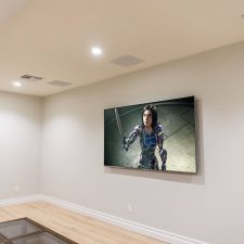 Media room with a wall-mounted television and in-ceiling speakers in Rancho Santa Fe.