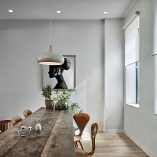Modern dining room with recessed ceiling lights and a pendant light above a long wooden table.