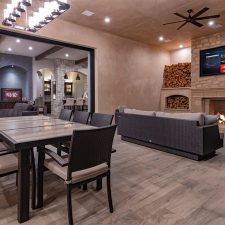 Covered patio with televisions, recessed speakers, dining area, and fireplace.
