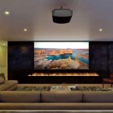 A casual home theater with a Sony projector and large screen above a fire feature.