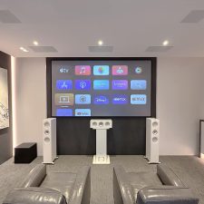 Custom home theater with projection screen, tower speakers, center speaker, in-ceiling speakers, and subwoofer